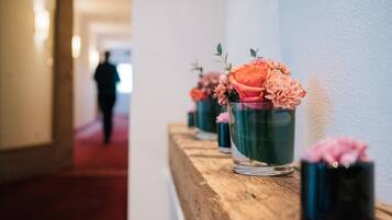 En gang med en træbænk, hvor der står vaser med blomster.