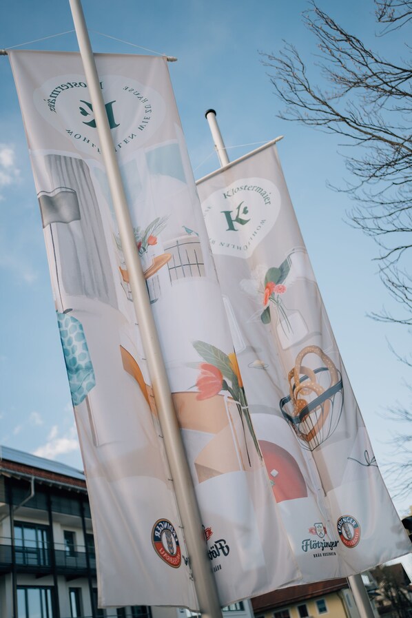Two vertical banners with various logos and illustrations, mounted on a pole.