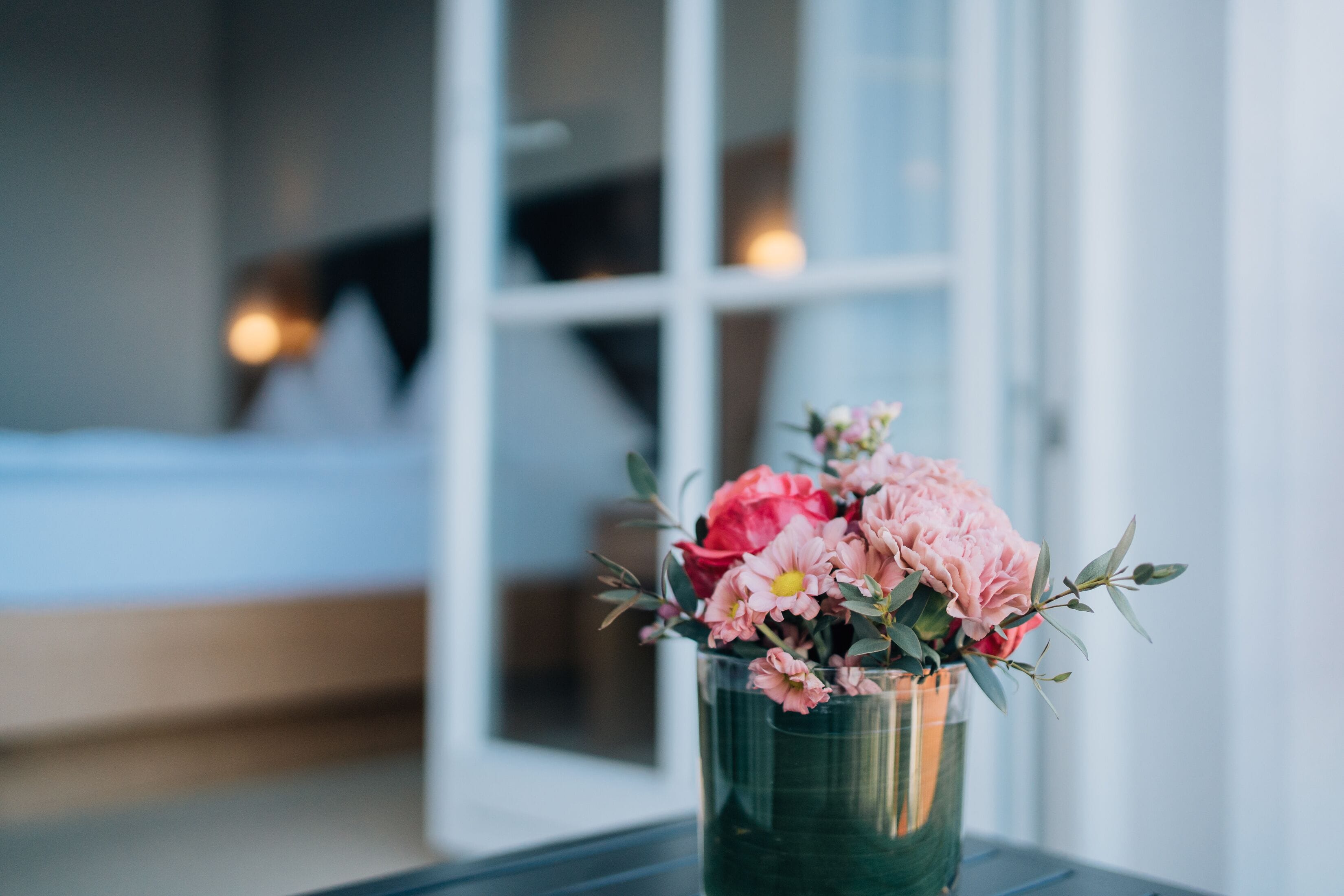 A glass vase with pink and red flowers on a table.