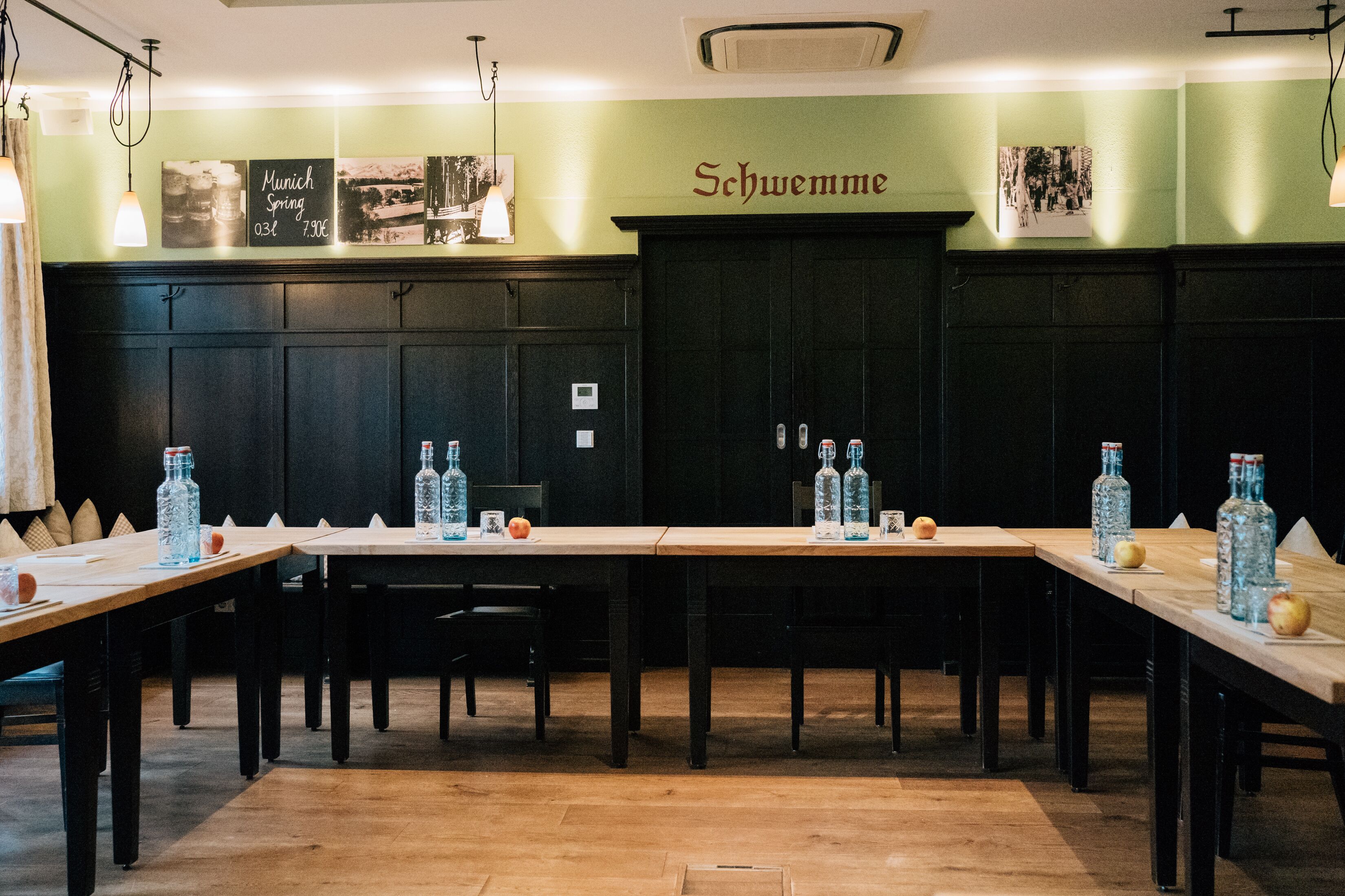 A restaurant with long wooden tables, chairs, and bottles of water.