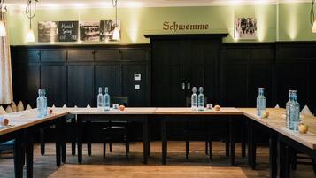 A restaurant with long wooden tables, chairs, and bottles of water.
