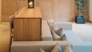 A modern interior with a wooden dining table, cushioned seating, and a large plant. - Klostermaier Hotel & Restaurant (Icking)