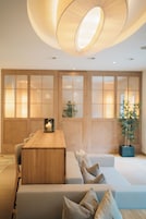A modern interior with a wooden dining table, cushioned seating, and a large plant.