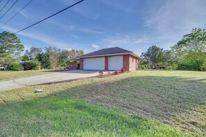 A single-story house with a garage, surrounded by a well-maintained lawn and trees. - Sunny Palm Bay Home w/ Screened Porch Near Beaches (Palm Bay)