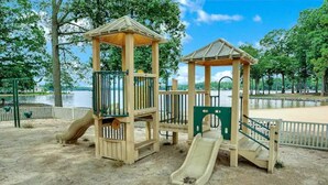 A playground with a slide and a climbing structure near a lake.