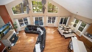 A spacious living room with a large black sectional sofa, a dining area with a round table, and a fireplace.