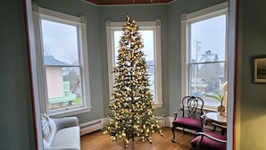 Une pièce avec un grand sapin de Noël, un canapé, un fauteuil et une petite table.