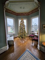 A room with a large Christmas tree, a sofa, a chair, and a small table.
