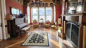 Un salon spacieux avec un grand piano, une cheminée et un grand miroir.