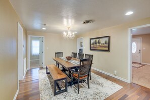 A dining area with a wooden table, chairs, a bench, and a chandelier.