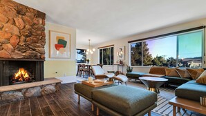 Uma sala de estar moderna com lareira de pedra, uma janela ampla e móveis contemporâneos.