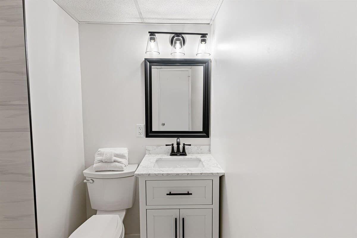 A modern bathroom with a toilet, sink, and mirror.