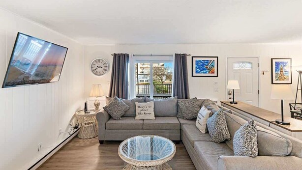 A living room with a sofa, a glass coffee table, a TV, and a window with curtains.