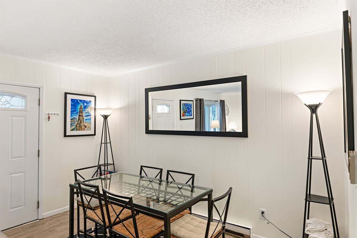 A dining area with a glass table and chairs, a large mirror, and a floor lamp.