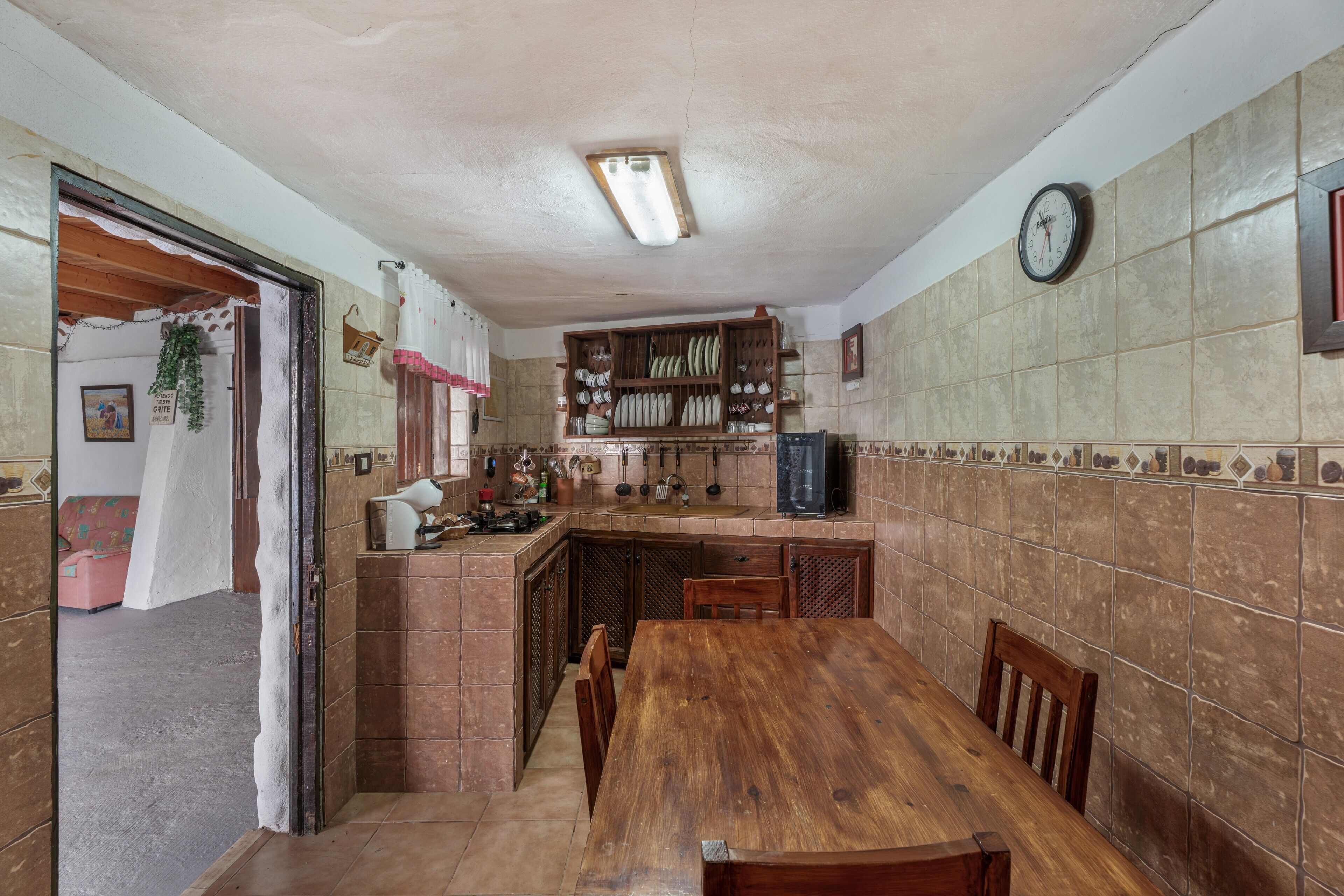 A kitchen with a wooden table, cabinets, and a clock on the wall.