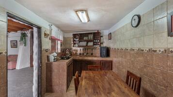 A kitchen with a wooden table, cabinets, and a clock on the wall.
