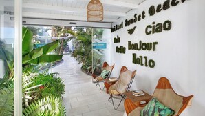 Un área de recepción con puerta de vidrio, un cartel de bienvenida y una pared con un mensaje en idioma extranjero.