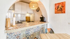 Una cocina con salpicadero de azulejos, lámpara colgante y un cuadro de toro en la pared.