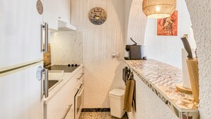 Una cocina compacta con horno integrado, un lavamanos y un microondas.
