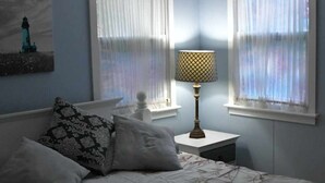 A bedroom with a bed, two nightstands, a lamp, and curtains.