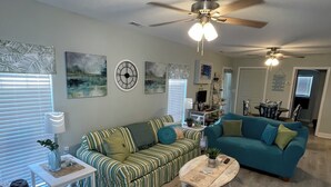 A living room with striped sofas, a round coffee table, and a ceiling fan.