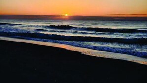 A sunset over the ocean with waves crashing onto the shore.