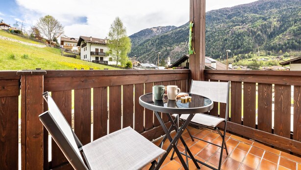 A balcony with a table, chairs, and a view of a mountainous landscape. - Apartment 'Collini Le Betulle' with Mountain View, Private Garden and Balcony (Spiazzo)