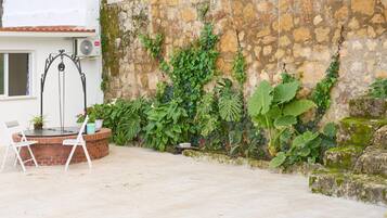 A patio with a swing set, a brick planter with plants, and a stone wall.