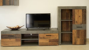 Un'elegante mobile porta TV moderno con televisore piatto, elementi in legno e cassetti integrati.