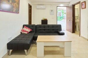 A modern living room with a black sofa, a wooden coffee table, and a small side table with bottles. - Holiday Home 'Villa Verde' with Shared Pool, Wi-Fi and Air Conditioning (Córdoba)