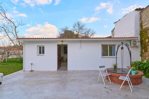 A small, single-story building with a tiled roof, a door, a window, and a small patio area with a table and chairs. - Holiday Home 'Villa Verde' with Shared Pool, Wi-Fi and Air Conditioning (Córdoba)