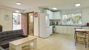 Una cucina moderna con mobili bianchi, un frigorifero e una zona pranzo con tavolo e sedie.