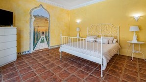 A bedroom with a bed, two bedside lamps, a TV, and a decorative archway. - Apartment 'Villa Colliure' with Sea View, Private Pool and Wi-Fi (Adeje)