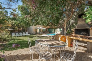 A patio with a grill, outdoor seating, and a pool.