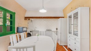A compact kitchen with white cabinets, a dining table, and a green window. - Apartment 'Villa Colliure' with Sea View, Private Pool and Wi-Fi (Adeje)