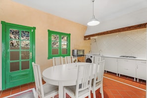A kitchen with white cabinets, a microwave, a washing machine, and a dining area with a white table and chairs.