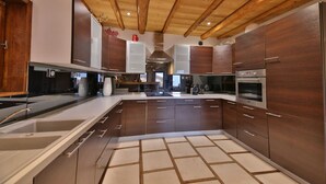 A modern kitchen with wooden beams, stainless steel appliances, and a central island.
