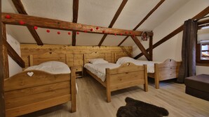 A room with three wooden beds, a wooden ceiling with exposed beams, and a bear rug on the floor.