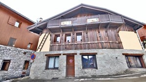 A wooden building with a stone base, multiple windows, and a balcony.