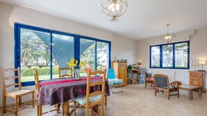 Uma sala de jantar com mesa, cadeiras e vista através de grandes janelas.
