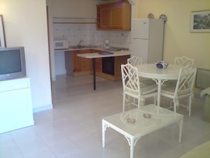 A compact living space with a dining area, kitchen, and a television.