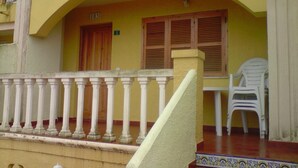 Un edificio con fachada amarilla, un balcón con barandilla blanca y una escalera que conduce a una puerta con el número 103.