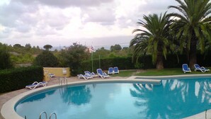 Una piscina con sillas de descanso y palmeras.