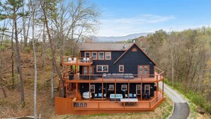 Eine zweistöckige Hütte mit Balkon, Terrasse und Whirlpool.