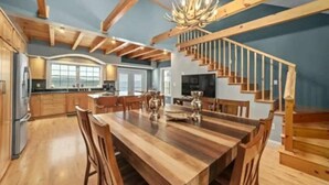 Eine geräumige Küche mit Holzausbau, einem großen Esstisch und einer Treppe, die in einen oberen Bereich führt.