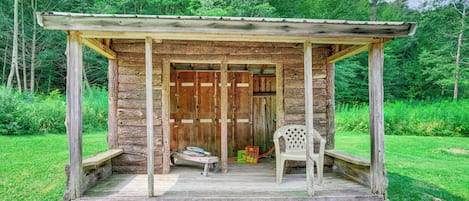Un rustico chalet in legno con veranda, una panca e una sedia.