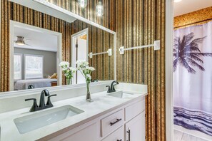 A bathroom with two sinks, a large mirror, and a shower curtain with a palm tree design. - Pensacola Home w/ Screened Porch: 10 Mi to Beach! (Pensacola)