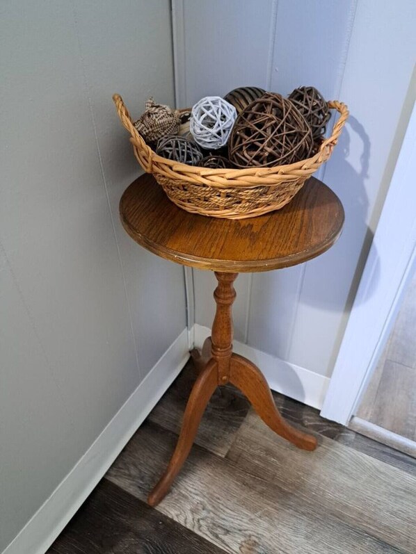 A corner table with a wicker basket containing decorative balls and a white spherical object.