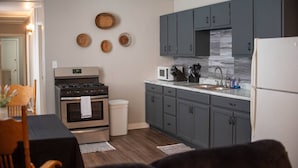 A modern kitchen with grey cabinets, a white countertop, and a stainless steel stove. - Charming Magnolia Apartment (Magnolia)