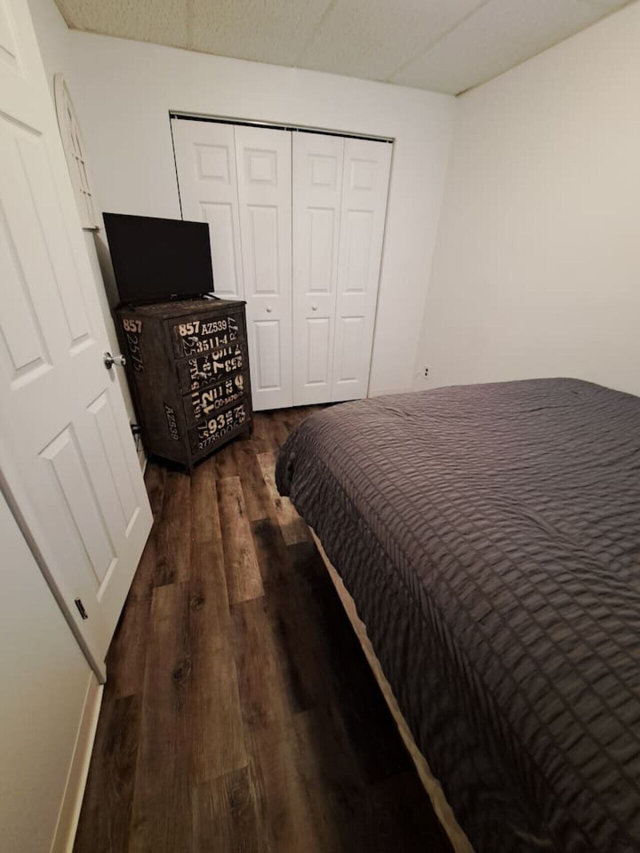 A bedroom with a bed, a wardrobe, and a chest of drawers.